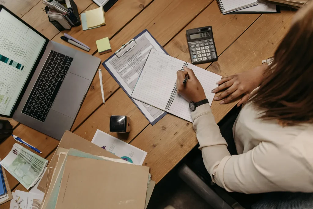 A focused Accounting Supervisor diligently working at her desk, surrounded by a laptop and papers.