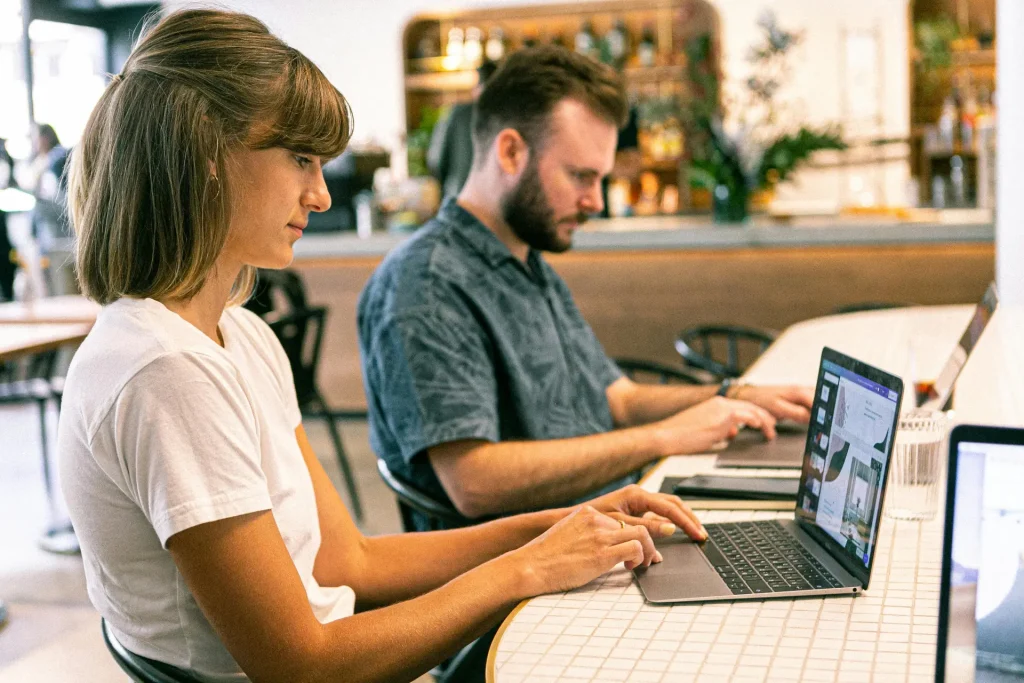 Two individuals from the Sales Marketing Team seated at a table with laptops.