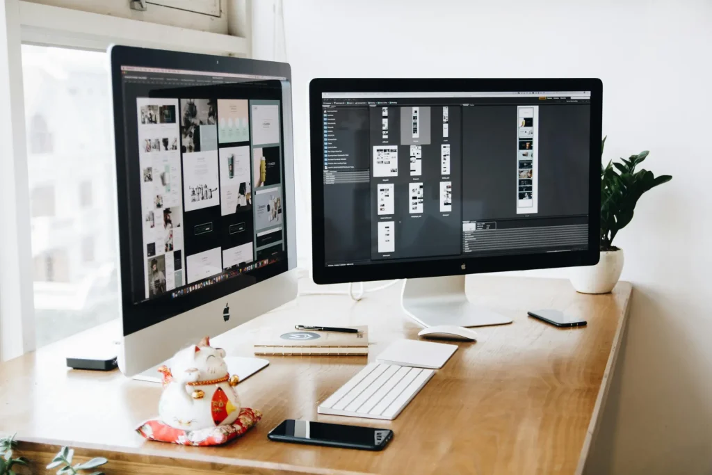 Two computer monitors on a desk, used by a website developer.