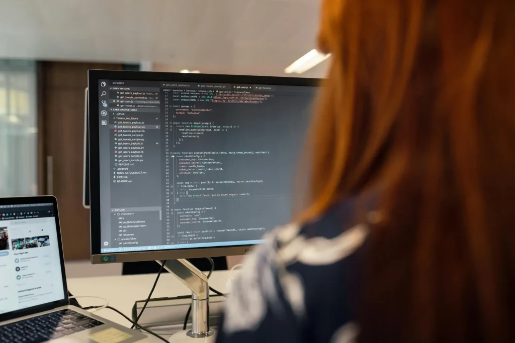 A System Engineer woman working on a computer with code displayed on the screen.