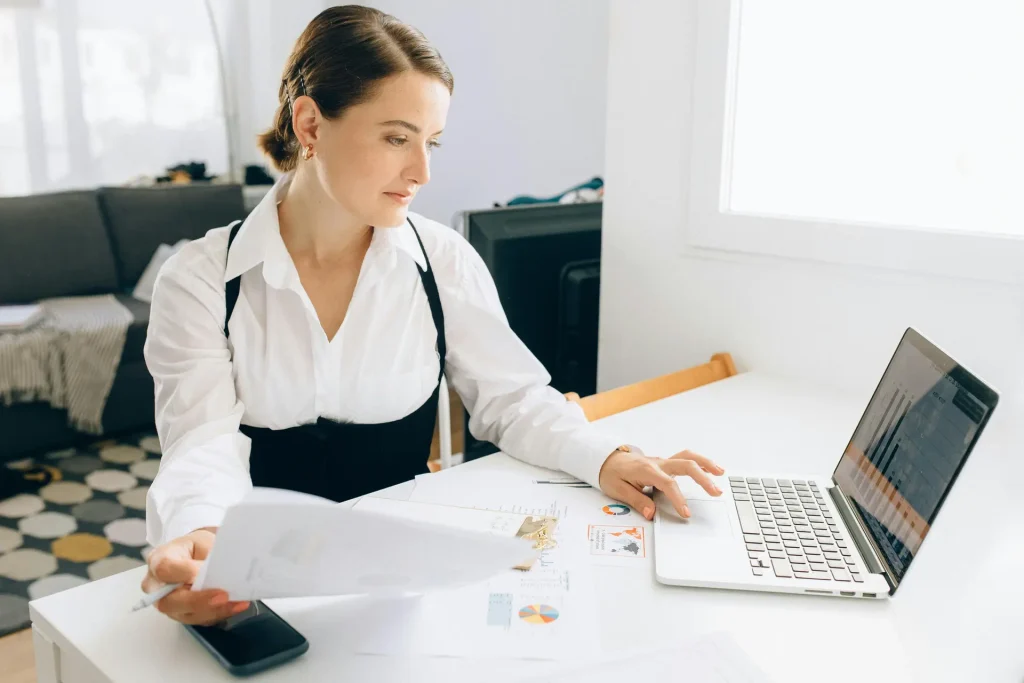 Image of a Sales Engineer woman working at a desk with a laptop and papers.