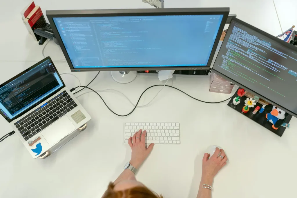 A technical support engineer sitting at a desk with two computer monitors, working diligently.