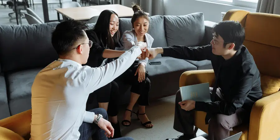 Group of people sitting on a couch, engaging in a casual meeting. Showcasing Filipino work culture, teamwork, and relaxed office environment.